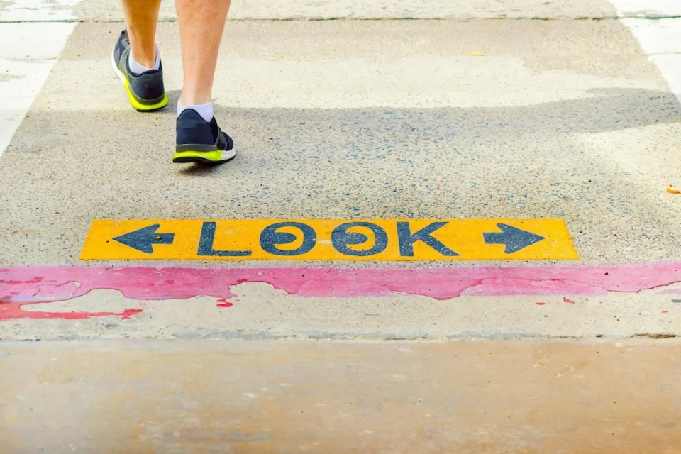 Close-up of "LOOK" sign on sidewalk with one pedestrian walking away.